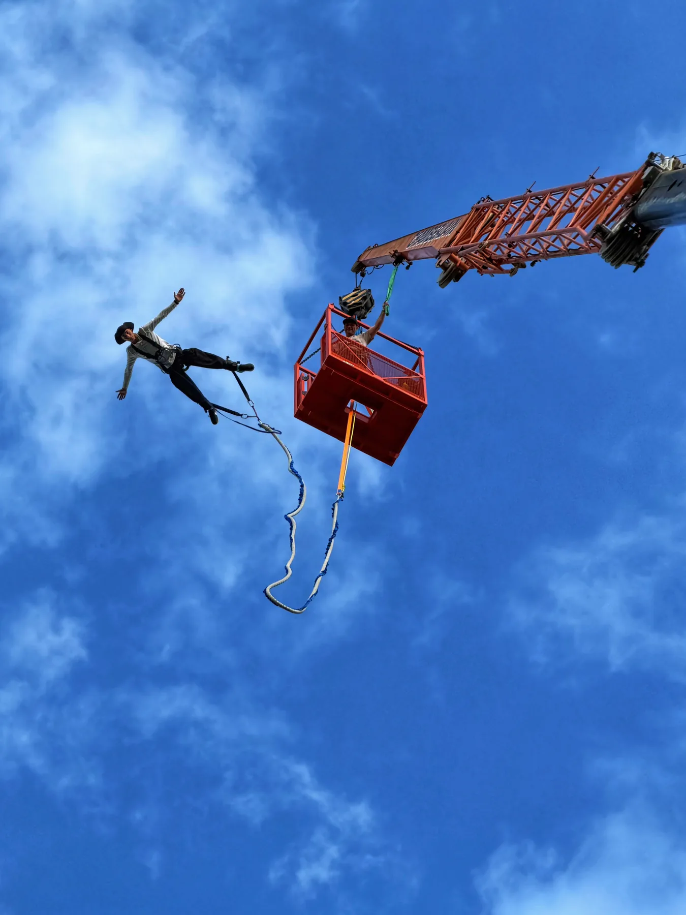 Skoczek bungee obok pomarańczowej platformy na tle nieba