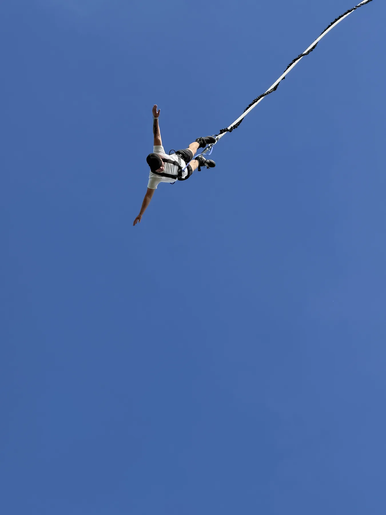 Skoczek bungee w locie na tle niebieskiego nieba